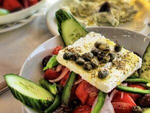 Horiatiki (Greek Village Salad) Ripe tomatoes, cucumbers, red onions, peppers, Kalamata olives, oregano, and feta  cheese.